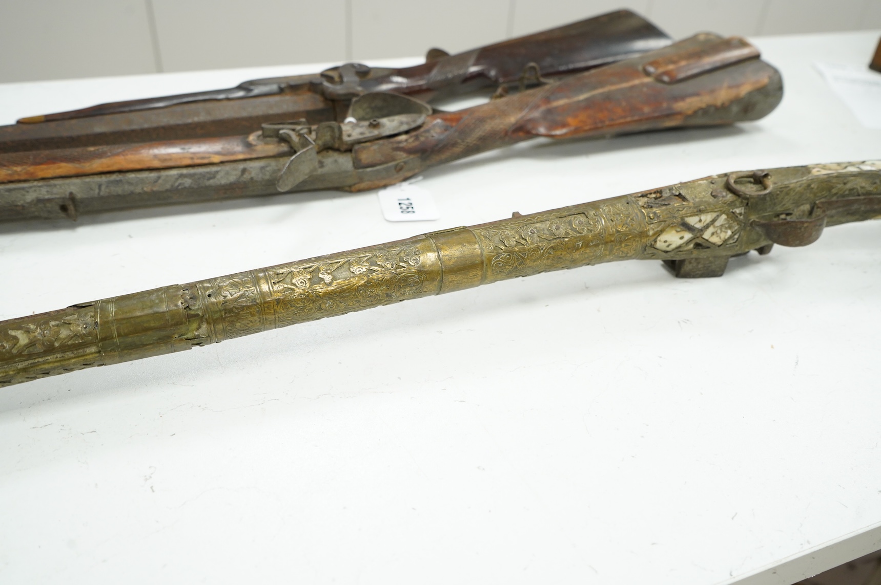 A Balkan miquelet flintlock gun with part octagonal Damascus twist barrel, silver inlaid at breach and muzzle, brass covered stock with shaped mother-of-pearl segments covering the butt, the side of stock inscribed ‘Piet